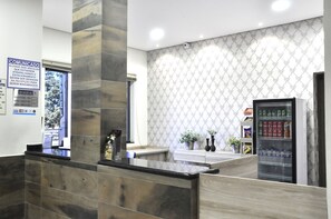 A reception area with a marble counter, a vending machine, and a patterned wall.
