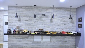 Zona de bufé con un fondo de pared de piedra, iluminación colgante y una variedad de alimentos.