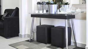 Una sala de estar moderna con un sofá negro, una mesa de centro con objetos decorativos y una alfombra estampada en blanco y negro.