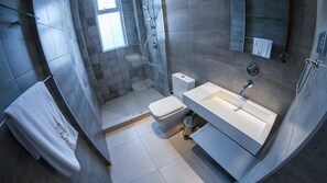 Une salle de bain moderne avec une douche à parois de verre, un lavabo blanc et des toilettes.