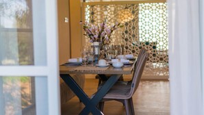 A dining table set with plates, glasses, and a vase of flowers.