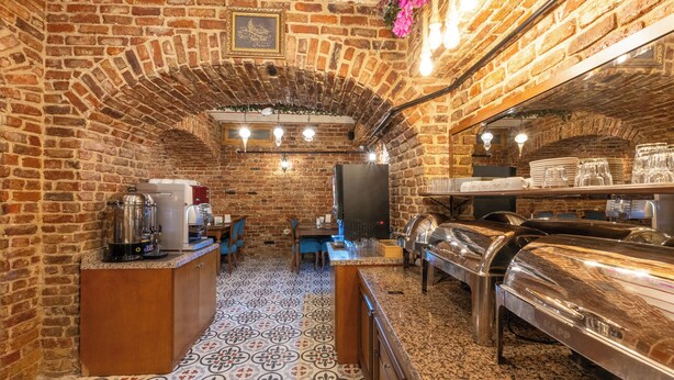 A brick-walled kitchen with a patterned floor, a coffee machine, a refrigerator, and a buffet setup. - Meserret Palace Hotel (Istanbul)