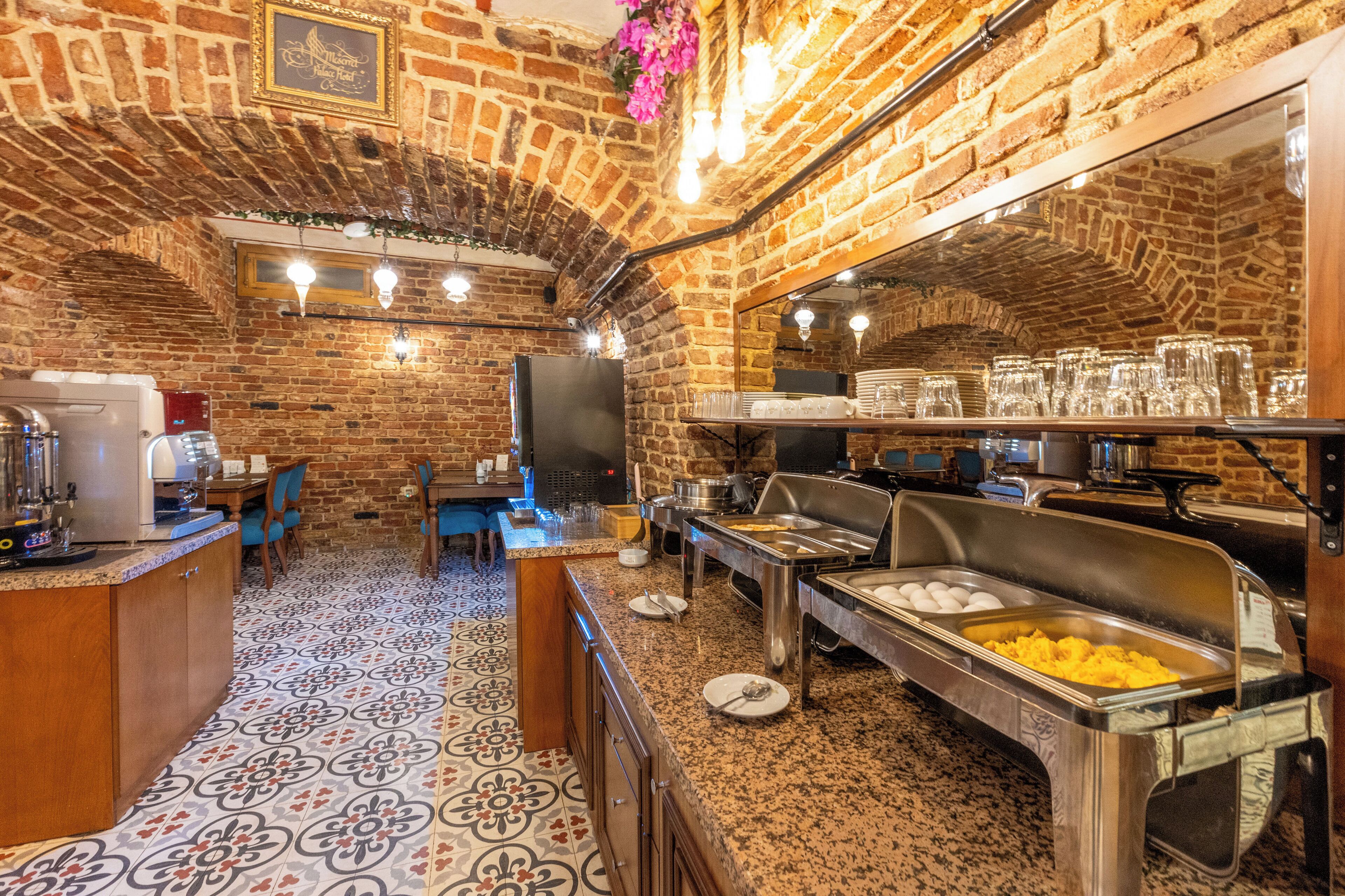 Un restaurant amb parets de maó, terra de rajola i taulells tipus bufet amb menjar i begudes.