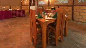 Een eetruimte met een lange houten tafel voor vier personen, omringd door houten stoelen.