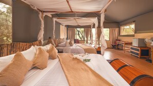 Een hemelbed met houten hoofdeinde, een bureau met stoel, en een kleine ventilator.