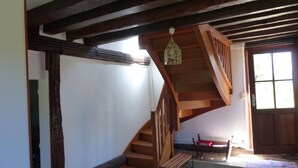 Una escalera de madera con un banco al pie, una lámpara colgante y una puerta con ventanas.