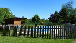 Zona de piscina con valla y una estructura de madera al fondo.