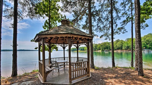 A wooden gazebo with a roof and a table and chairs inside, surrounded by trees and overlooking a lake. - Lake Keowee Resort Condo w/ Balcony & Pool Access! (Salem)