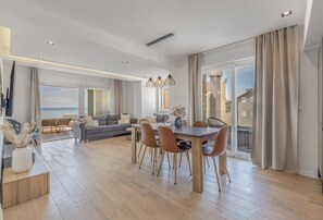 Un soggiorno moderno con zona pranzo, ampie finestre e vista mare.