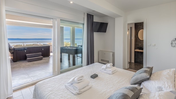 A hotel room with a bed, a TV, a bathroom, and a view of the sea. - Luxury Apartment with Hot tube! Villa Collis (Makarska)
