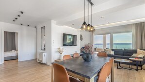 A modern living room with a dining area, large windows, and a view of the sea. - Luxury Apartment with Hot tube! Villa Collis (Makarska)