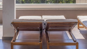 A balcony with two wooden lounge chairs, a view of the sea, and a distant cityscape. - Luxury Apartment with Hot tube! Villa Collis (Makarska)