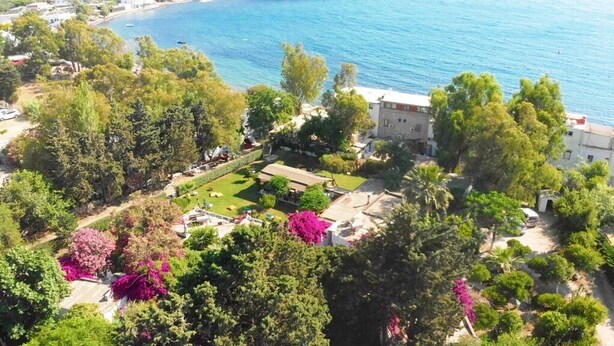 An aerial view of a coastal property with a well-maintained garden, a tennis court, and a building adjacent to the sea. - Myndos Bed & Breakfast (Bodrum)
