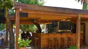 A wooden outdoor bar area with stools, a chalkboard menu, and potted plants. - Myndos Bed & Breakfast (Bodrum)