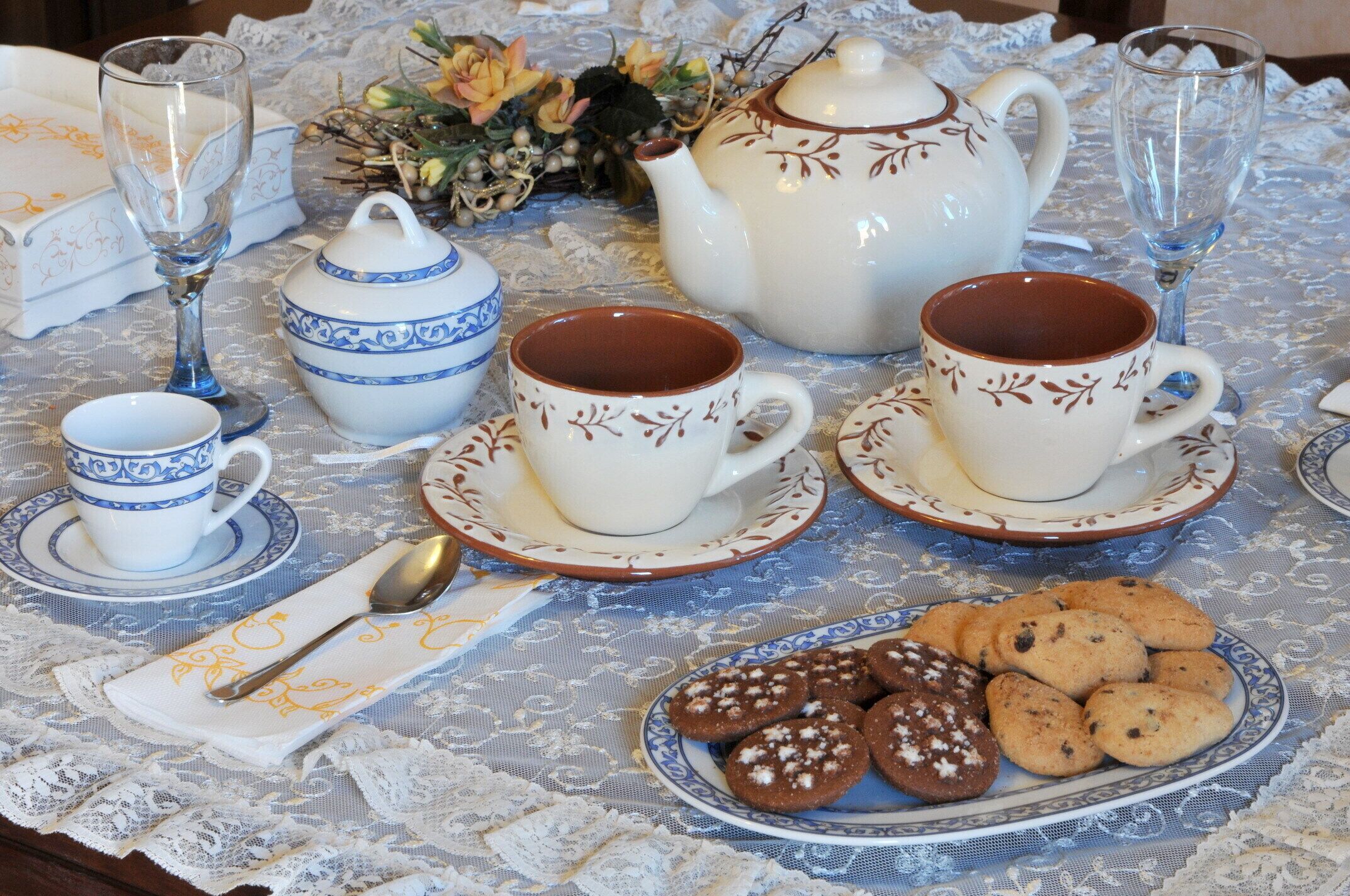 A table set with tea cups, a teapot, and cookies.