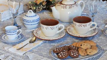 A table set with tea cups, a teapot, and cookies.