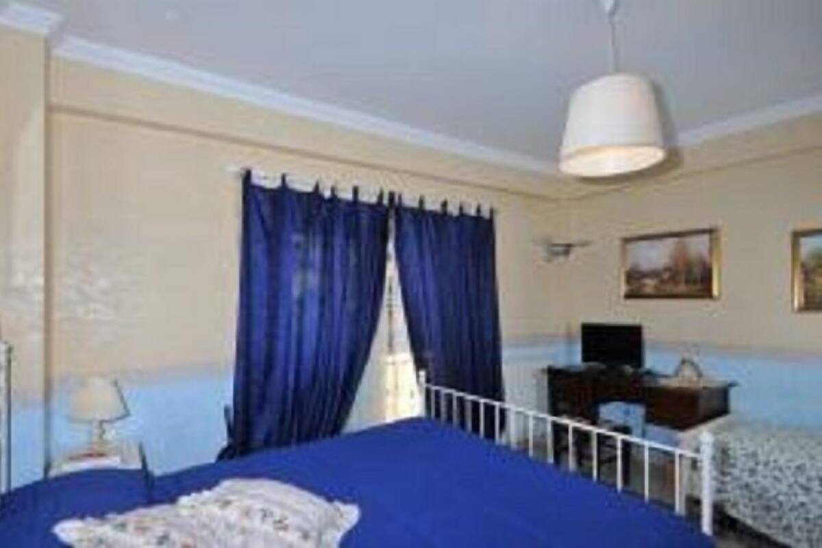 A bedroom with a single bed, a desk, a chair, and a hanging lamp.