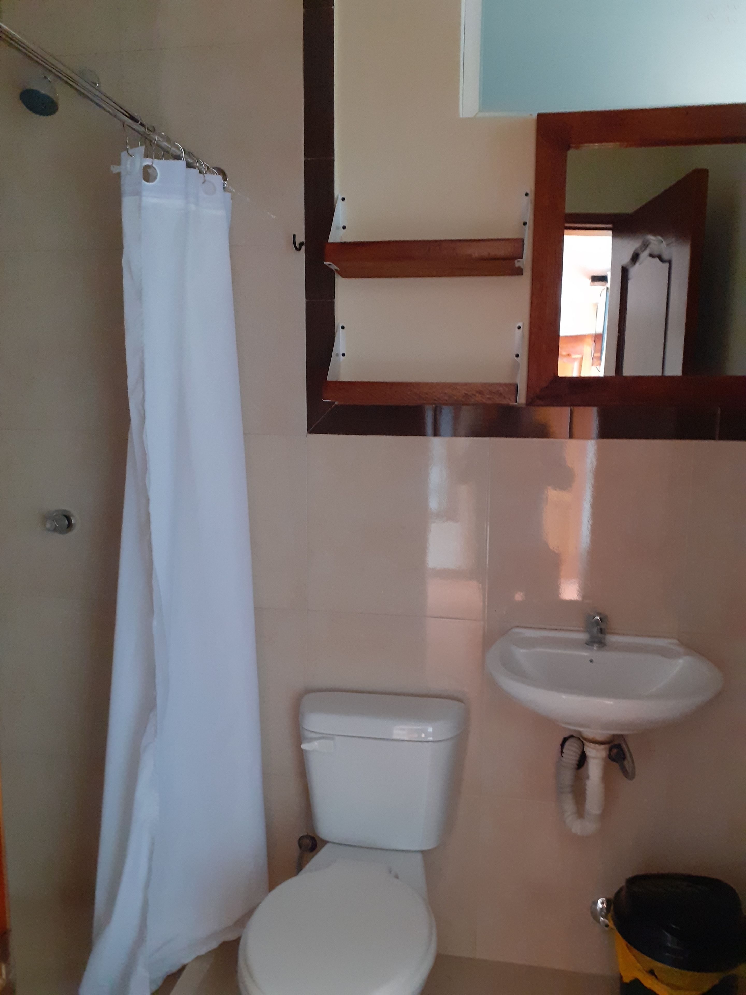 Baño con inodoro, lavamanos y cortina de ducha.