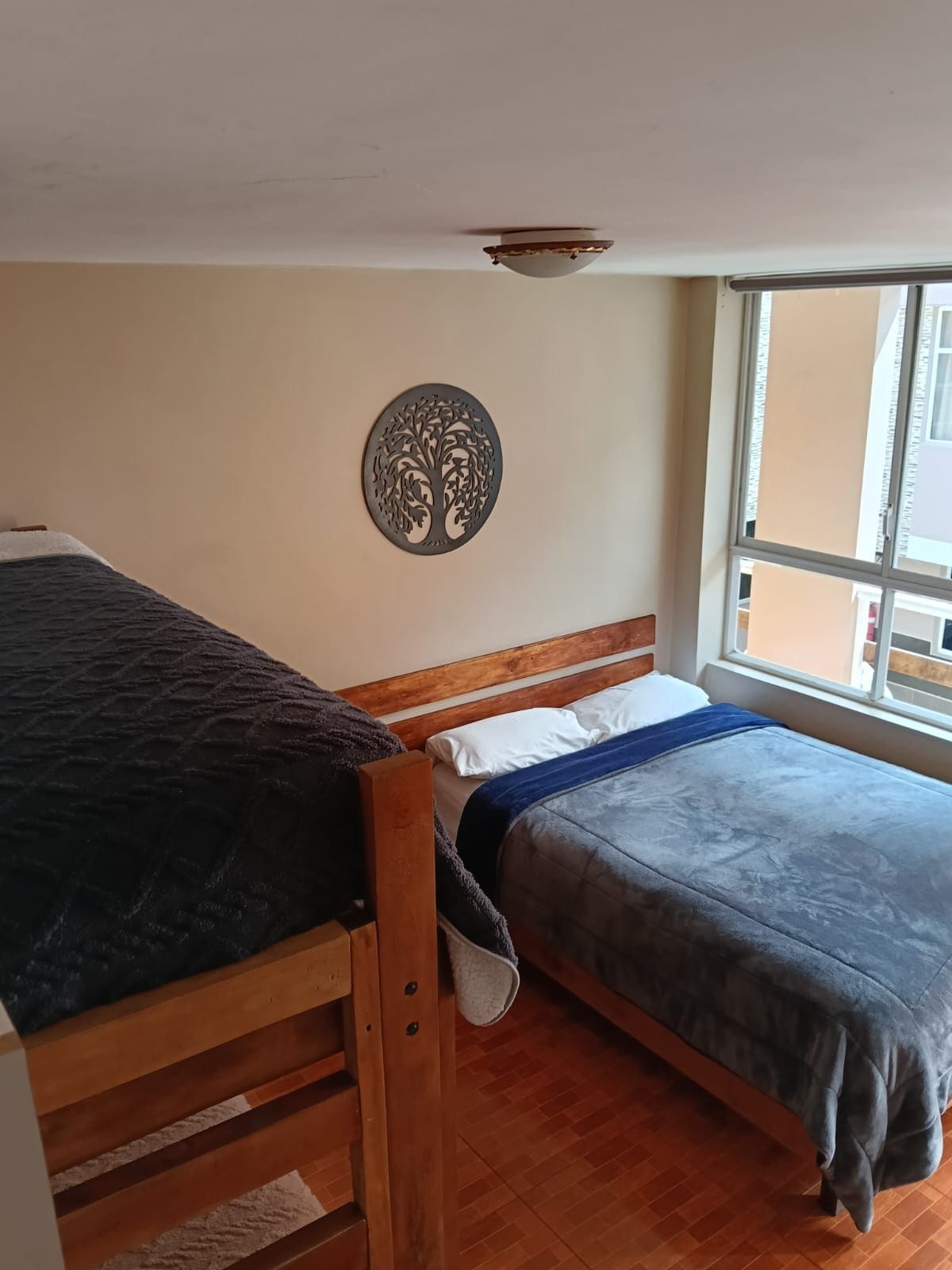 Una habitación con dos camas de madera, una ventana con vistas y un adorno en la pared.