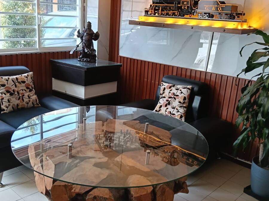 A modern living room with a glass-top coffee table, a sofa, and a decorative shelf with a model train.