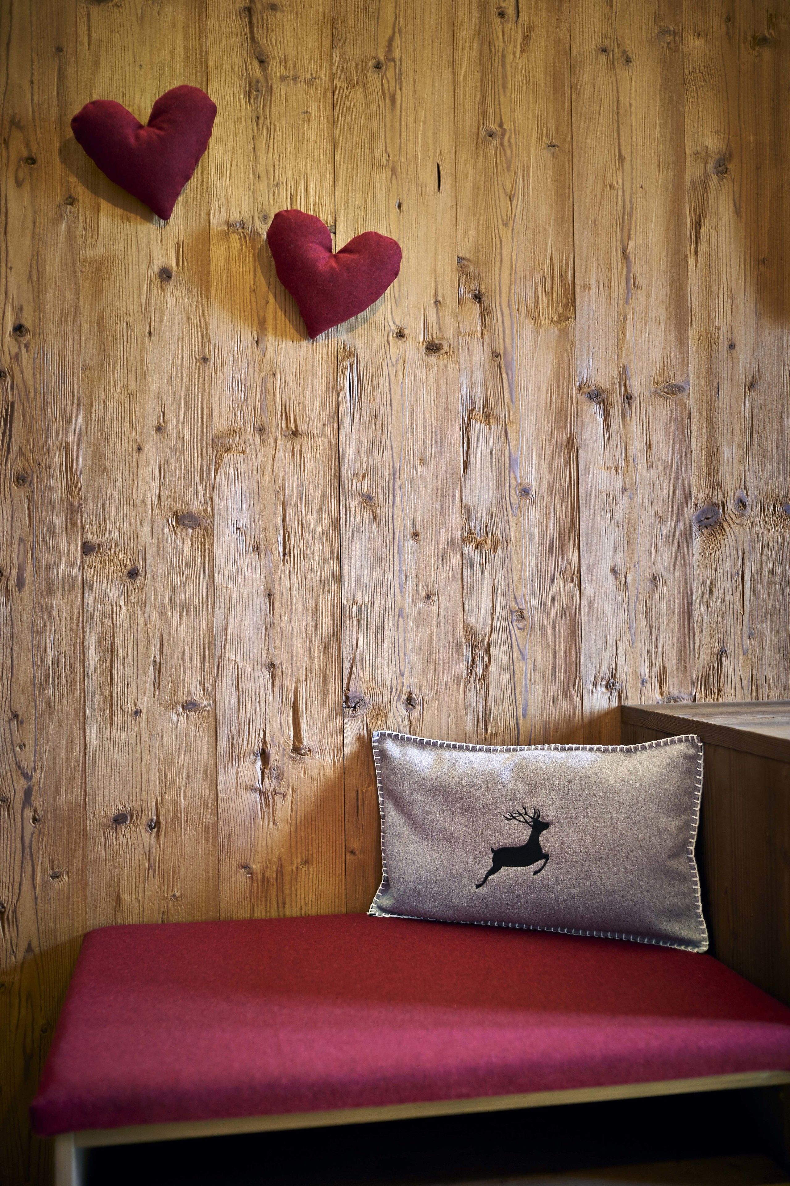 Een houten wand met twee decoratieve hartjes en een kussen met een silhouet van een hert.
