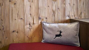 Een houten wand met twee decoratieve hartjes en een kussen met een silhouet van een hert.