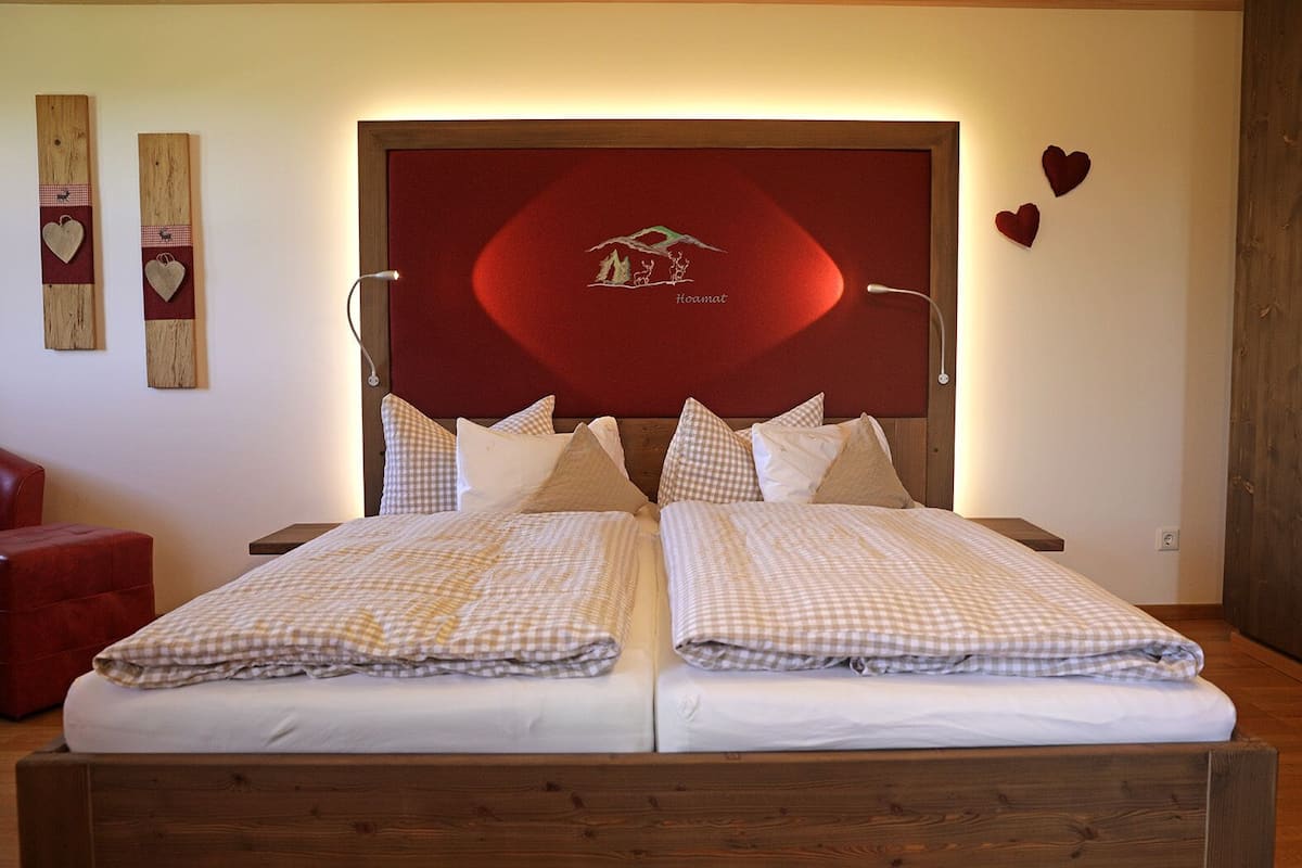 A double bed with a checkered bedspread, a wooden headboard, and two heart-shaped wall decorations.