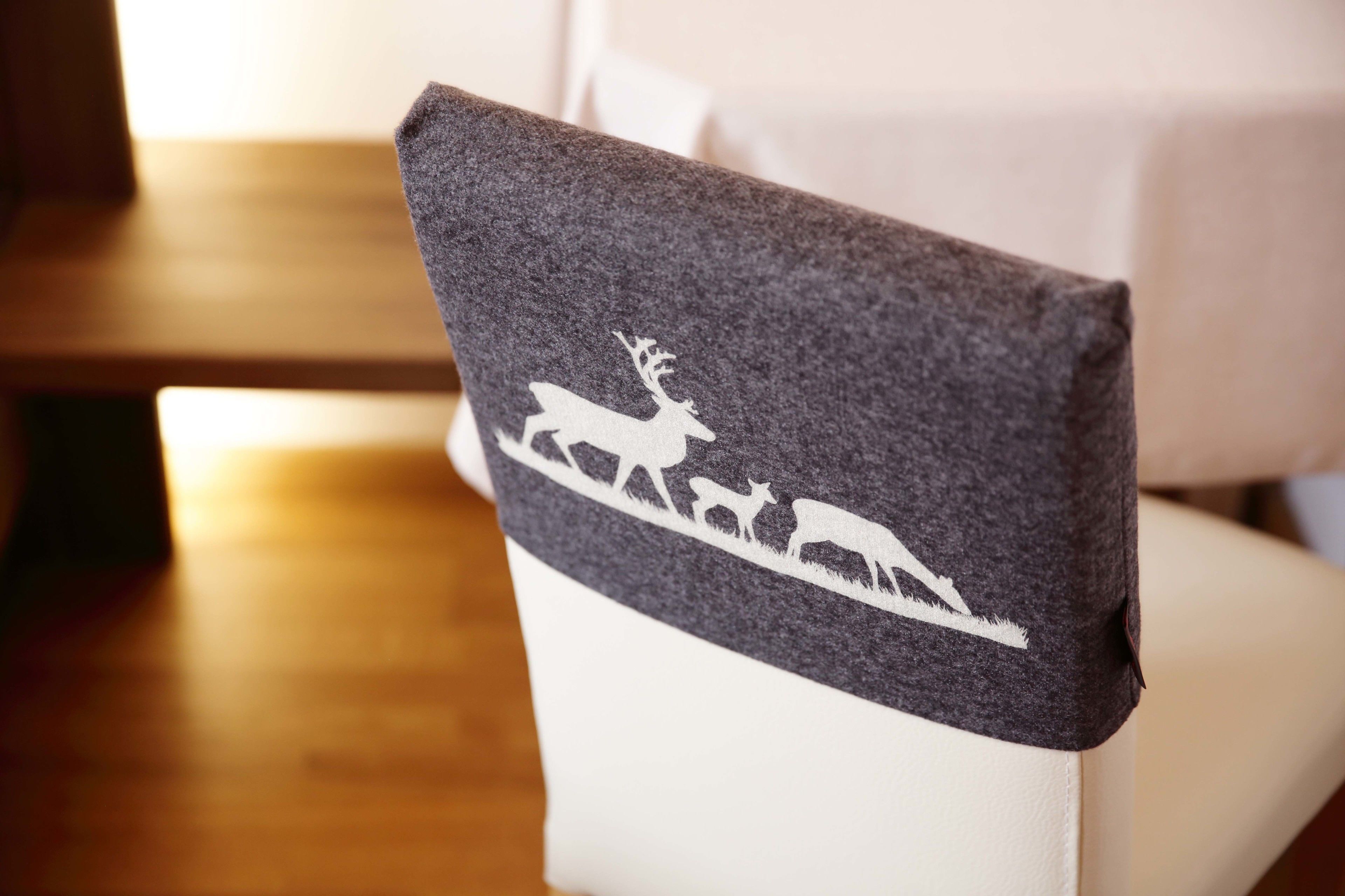 A chair with a gray felt cover featuring a white deer and antlers silhouette.