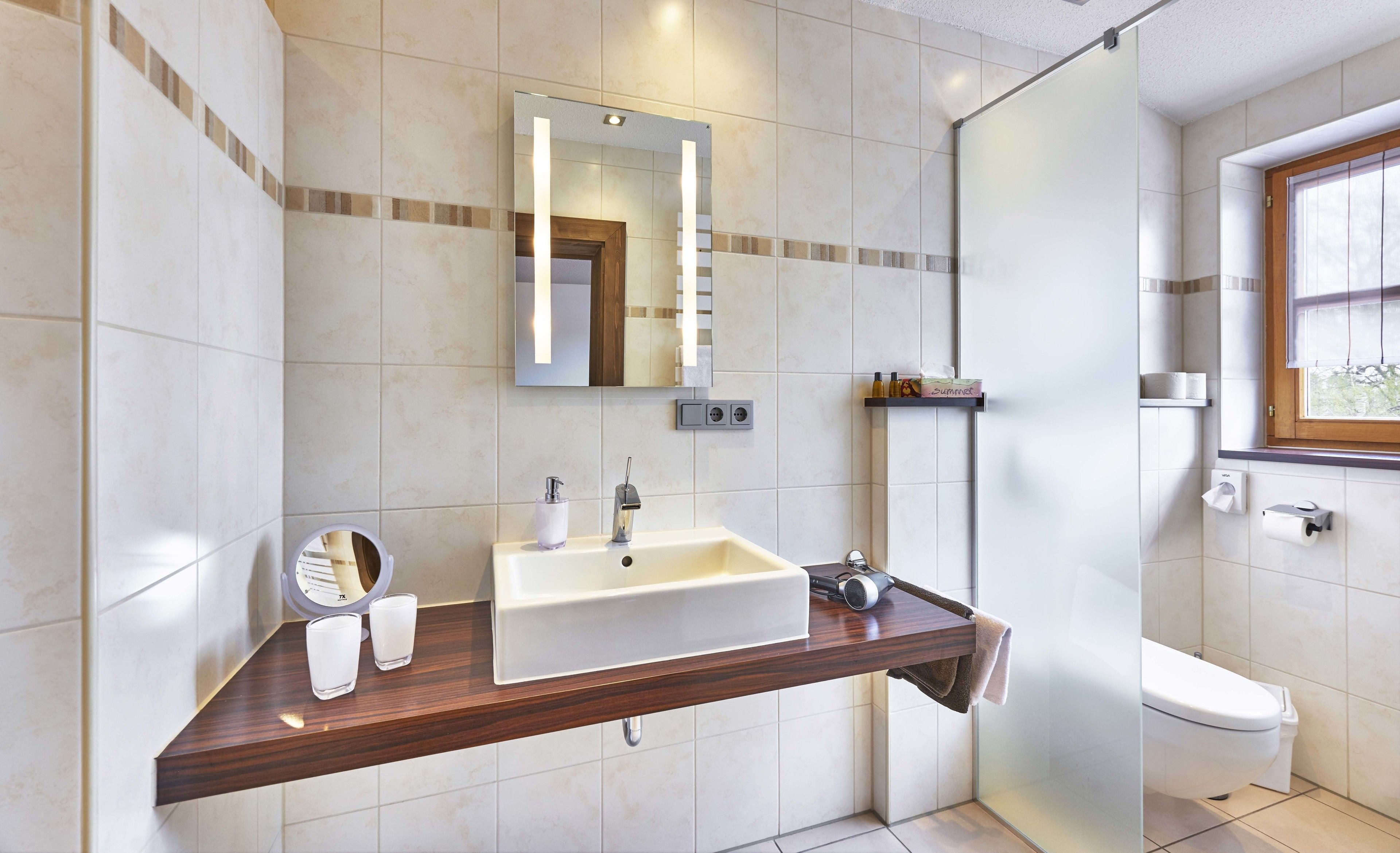 Un baño moderno con un espejo grande, un lavabo y un inodoro.