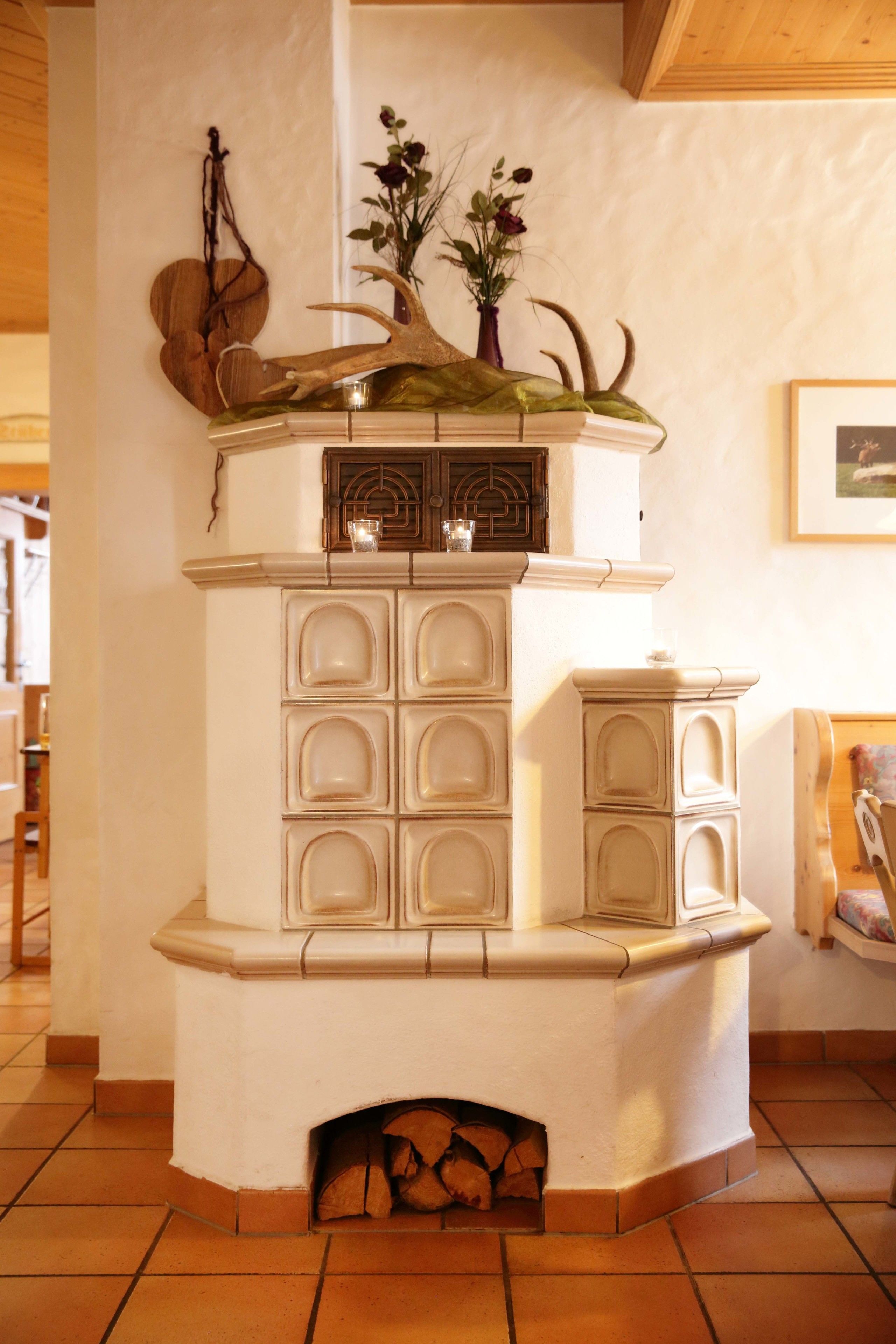 Una chimenea en esquina con un revestimiento decorativo, un jarrón con flores y un cuadro en la pared.