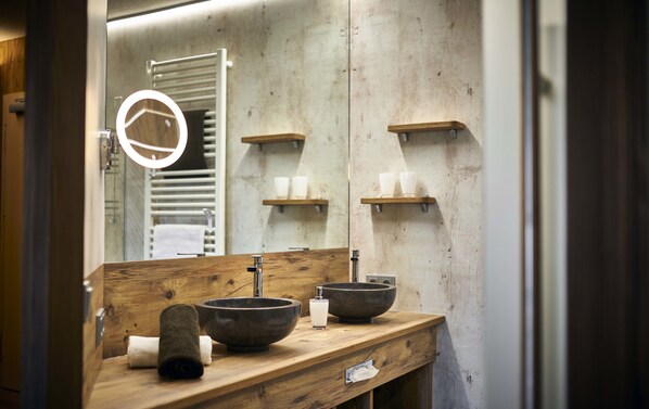 A bathroom with a wooden vanity, two large bowls, a small bottle, and a towel. - Schätzlhof (Ruderting)