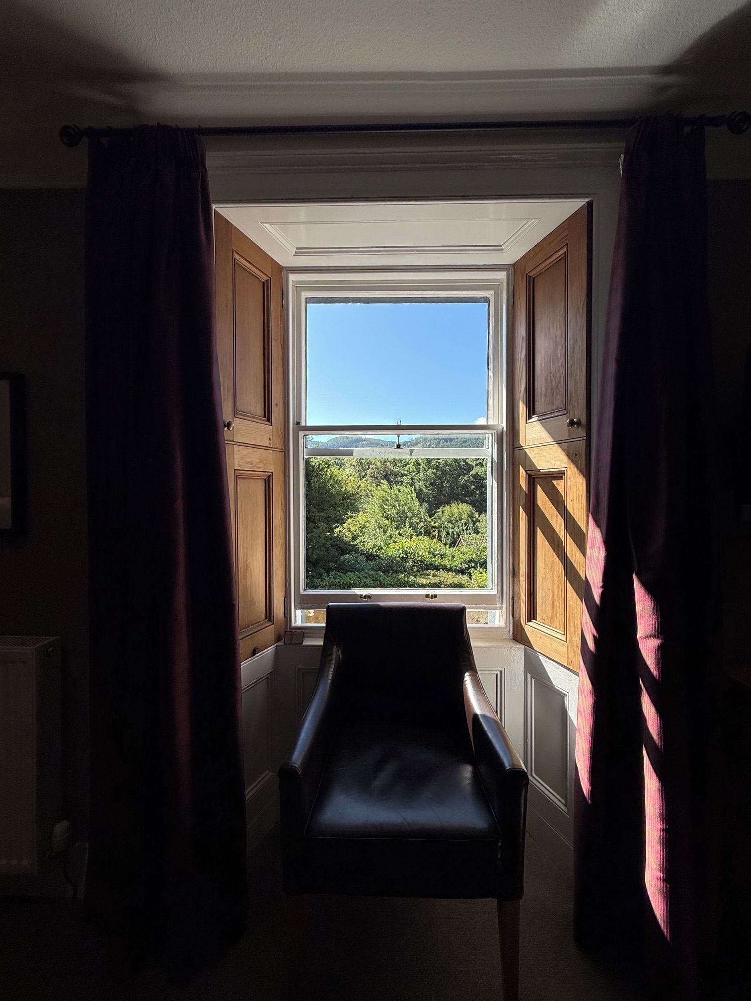 A room with a window, a chair, and curtains.
