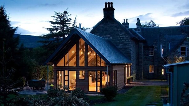 A stone house with a large glass windowed room, surrounded by a garden and trees. - Craigatin House & Courtyard (Adults only) (Pitlochry)