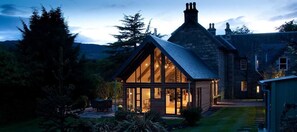A stone house with a large glass windowed room, surrounded by a garden and trees. - Craigatin House & Courtyard (Adults only) (Pitlochry)