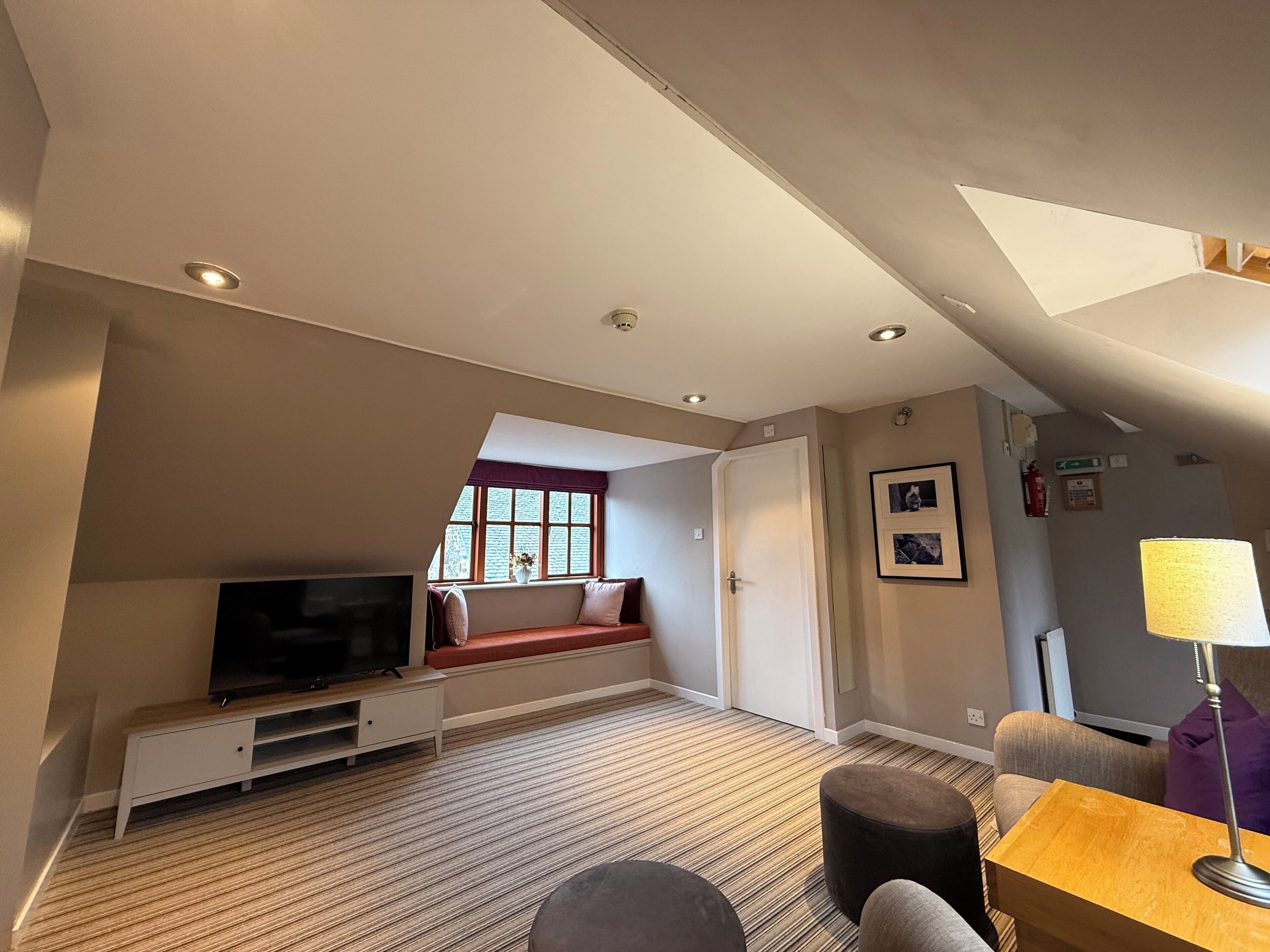 A modern hotel room with a television, seating area, and a window with a view.
