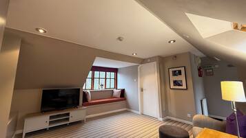 A modern hotel room with a television, seating area, and a window with a view.