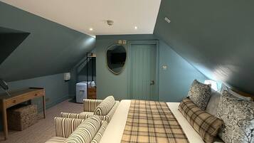 A bedroom with a bed, a sofa, a desk, and a mirror.
