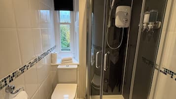 A modern bathroom with a toilet, a glass-enclosed shower, and a window with a view.
