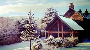 A cabin with a sloped roof, surrounded by snow-covered trees and a clear sky. - Craigatin House & Courtyard (Adults only) (Pitlochry)