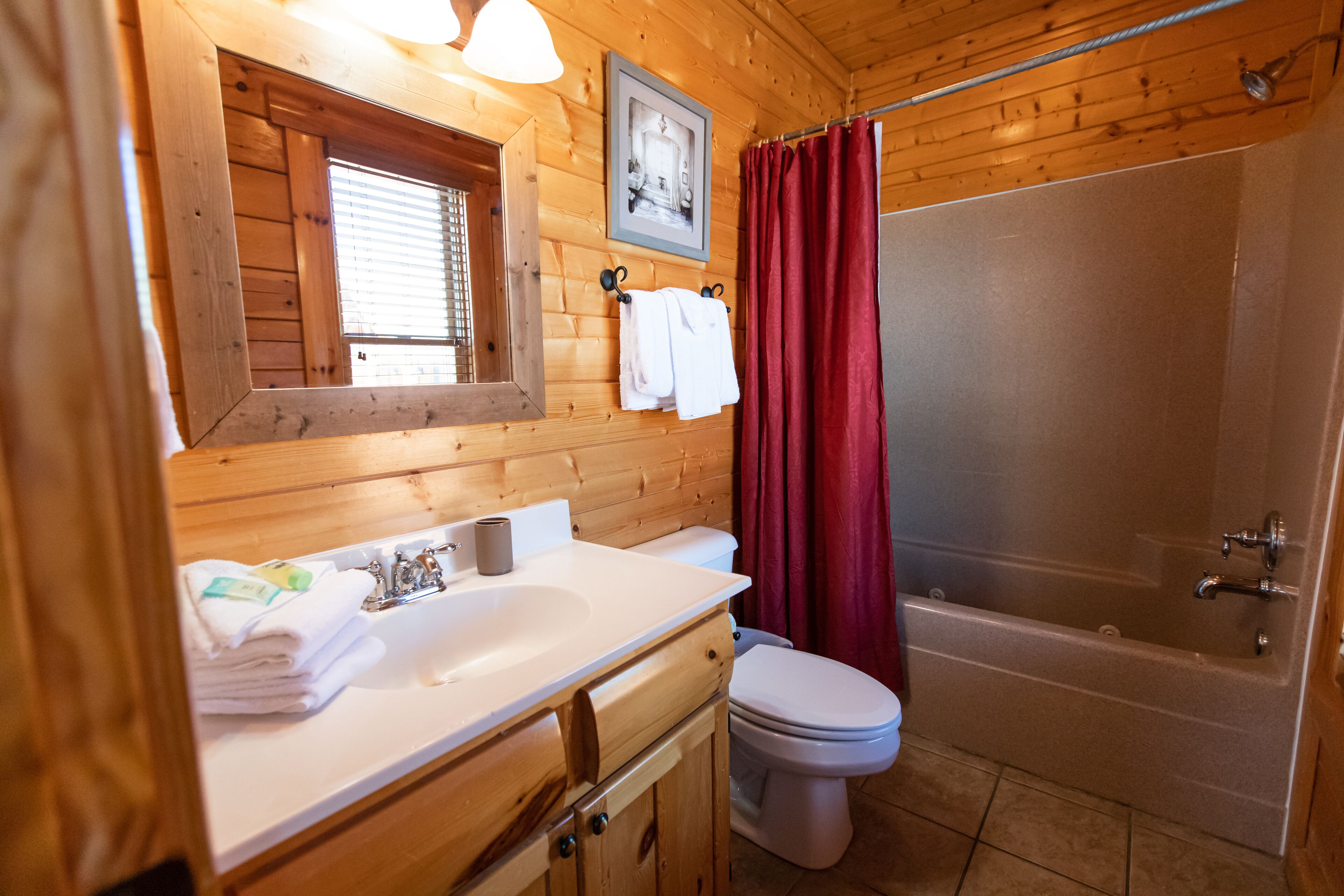 A wooden cabin bathroom with a sink, toilet, and bathtub.