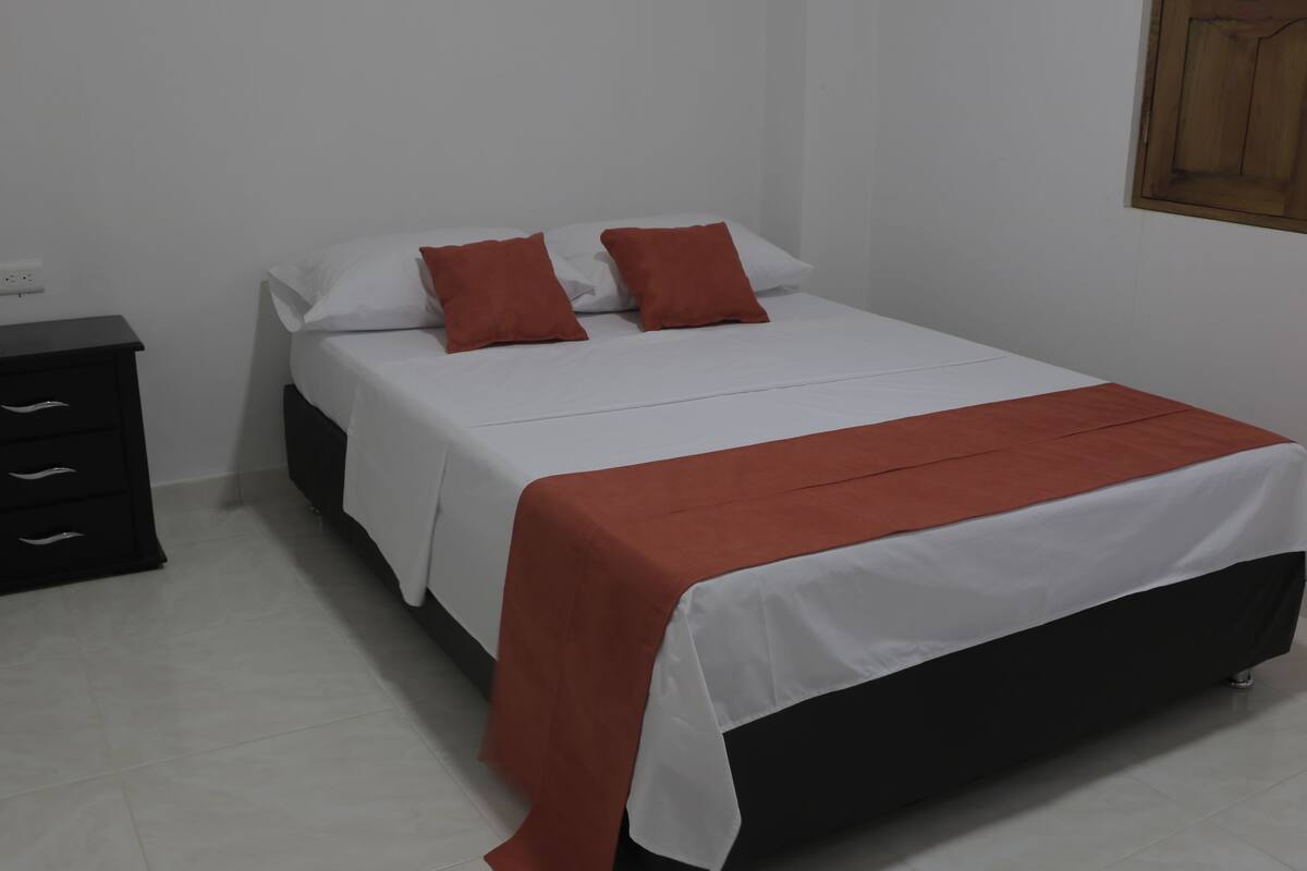 Une chambre à coucher comprenant un lit, une table de chevet et un meuble fixé au mur.