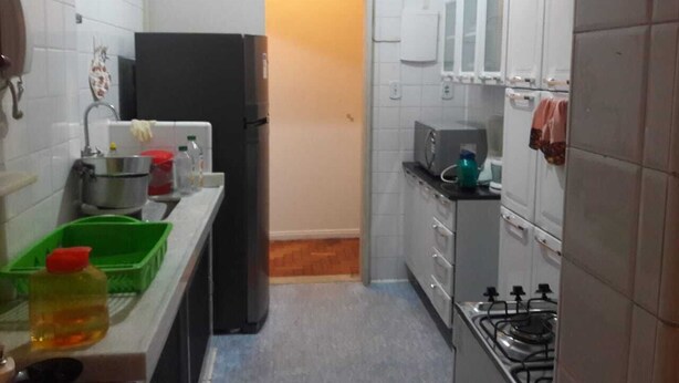Une cuisine de taille réduite avec des meubles blancs, un réfrigérateur, une cuisinière et un four à micro-ondes.