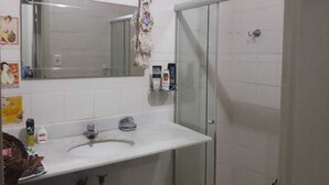 Une salle de bain avec un lavabo blanc, un miroir et une cabine de douche en verre.