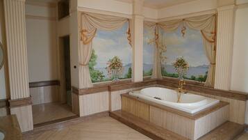 Ein geräumiges Badezimmer mit einer großen Badewanne, Marmorböden und dekorativen Wandgemälden.