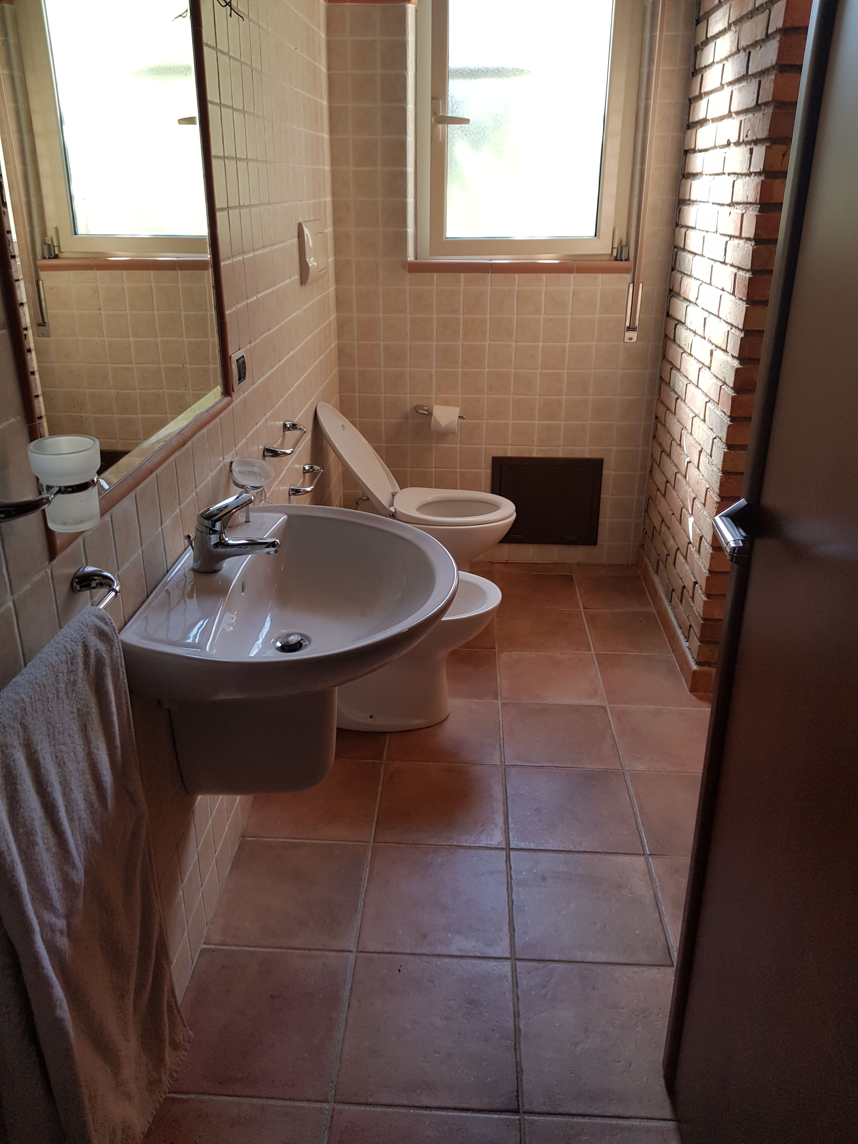 Une salle de bain avec un lavabo, des toilettes et une fenêtre.