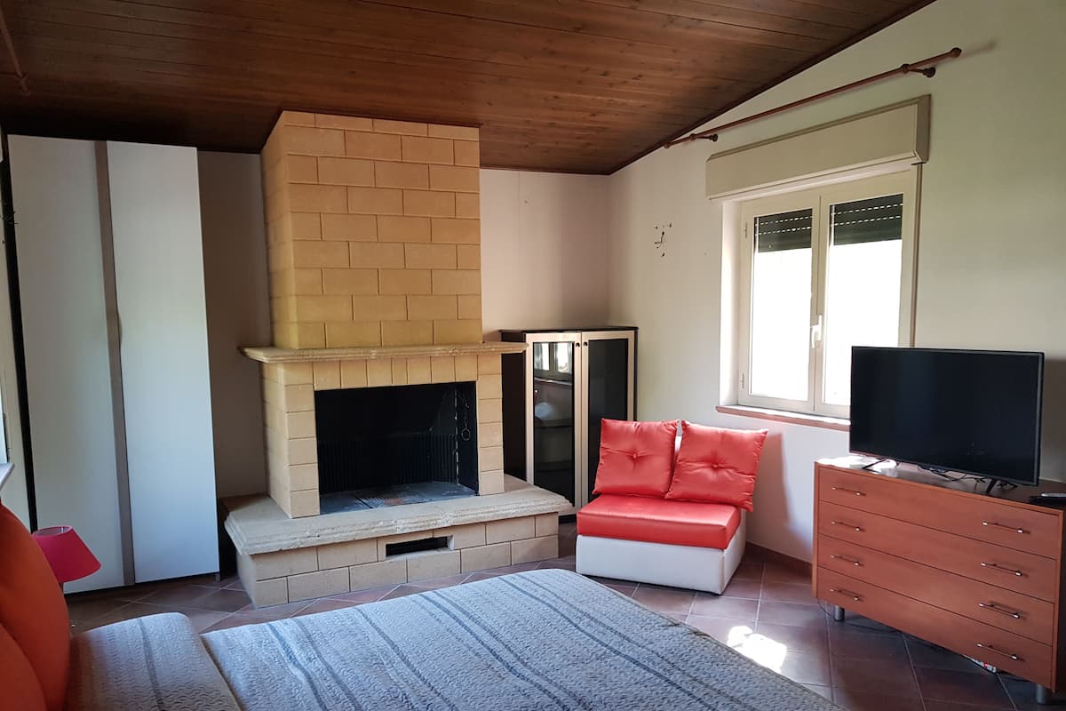 A living room with a fireplace, a television, a sofa, and a window.