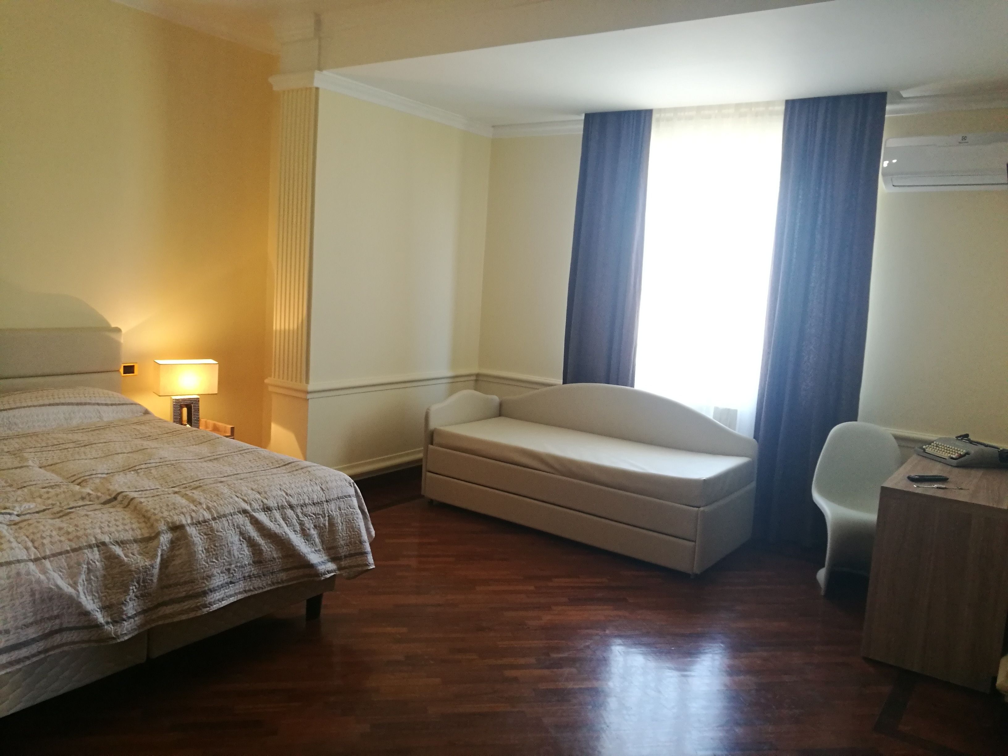 Een hotelkamer met een bed, een bureau, een stoel en een kleine bank.
