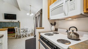 Cocina compacta con estufa, microondas y tetera. Cuenta con un comedor con mesa y sillas.