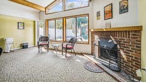 Una habitación acogedora con chimenea, ventanas amplias y sillones de mimbre.