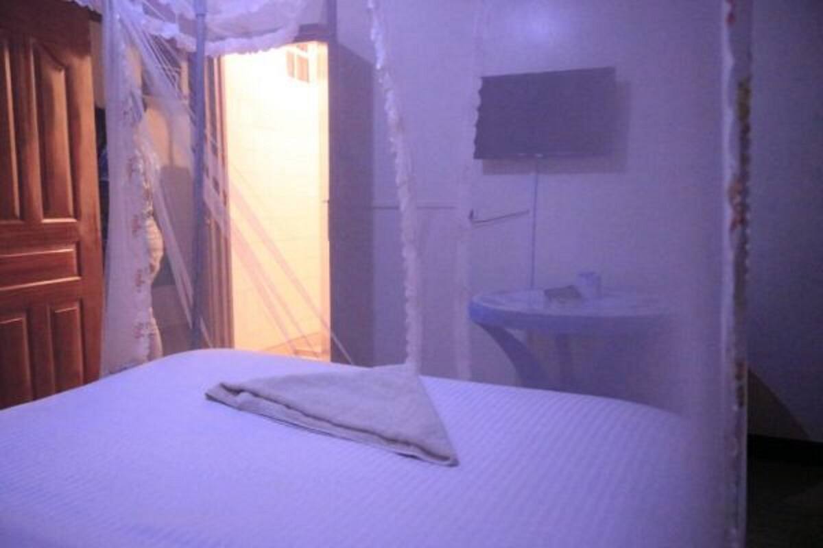 Una habitación con una cama, una mesita redonda y un televisor montado en la pared.